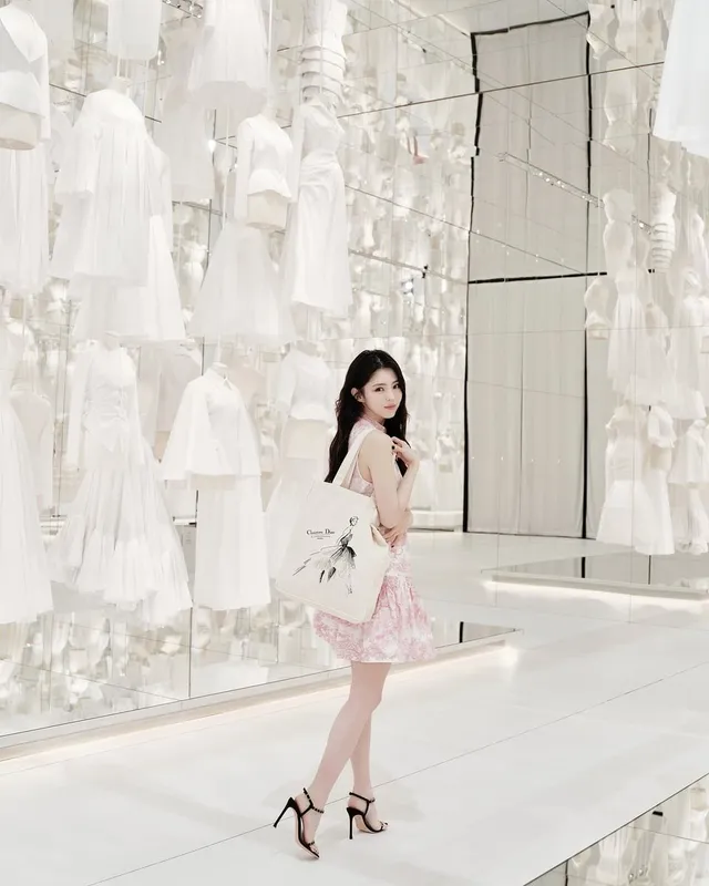 Han So-hee posing in a pink dress and black heels at a display.
