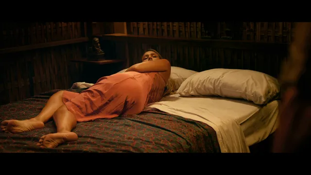 Jessica Alba reclining barefoot on a bed in a screen scene.