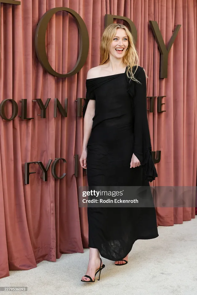Sarah Pidgeon posing in a black dress and open-toe heels on a carpet.