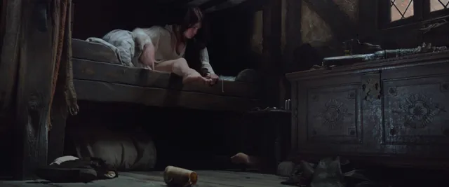 Gemma Arterton leaning over furniture in a dimly lit scene.