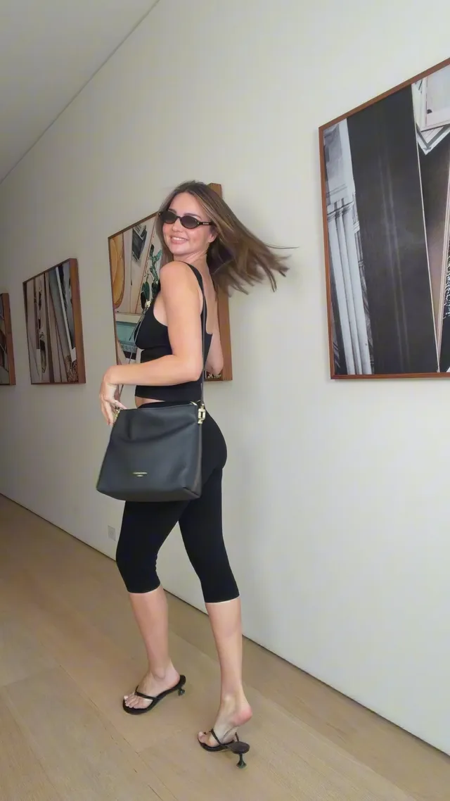 Miranda Kerr a black outfit and sandals in a hallway.