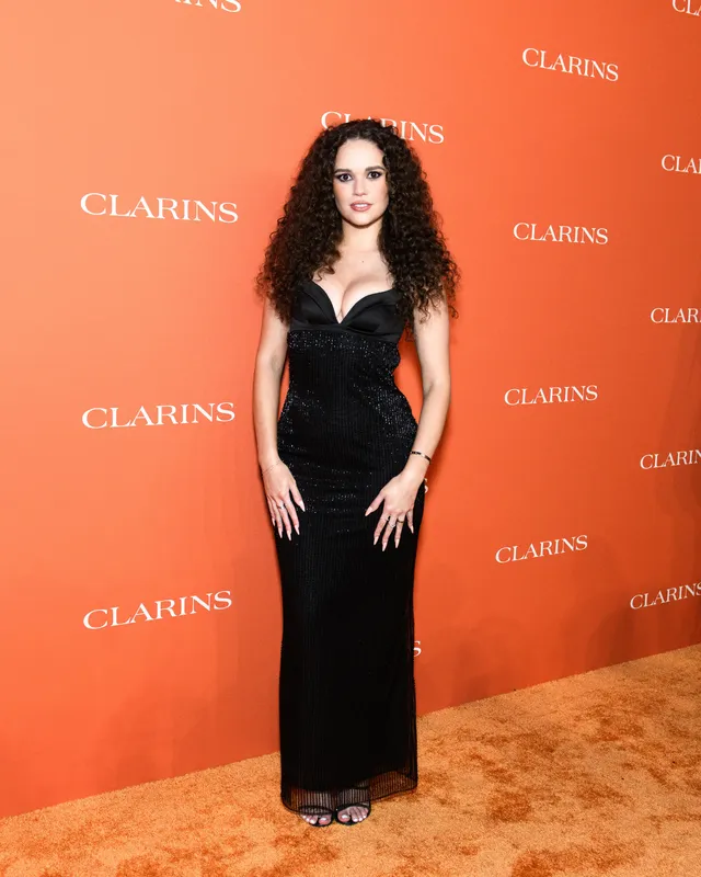 Madison Pettis wearing a long black dress and heels at an event.