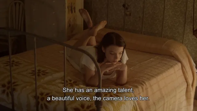 Anya Taylor-Joy lying barefoot on a bed in a screen scene.