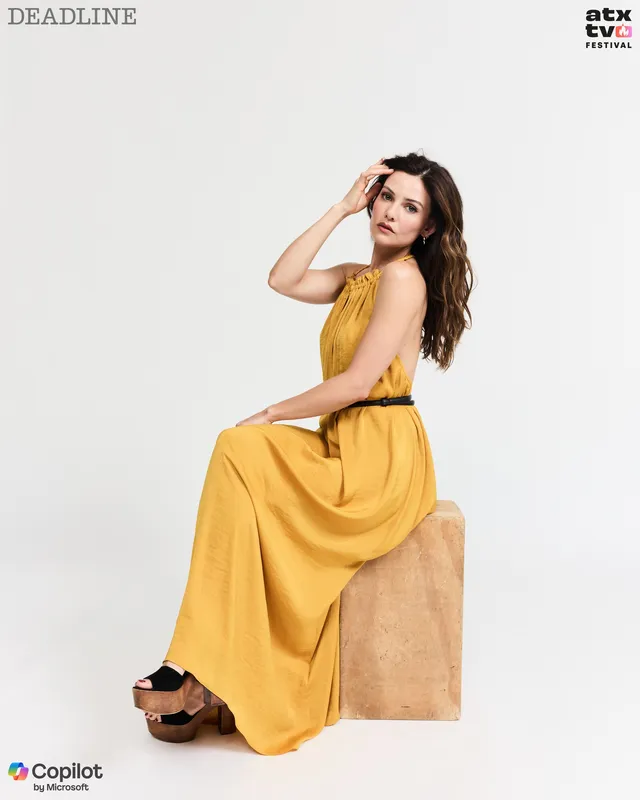 Danielle Campbell sitting for a studio portrait in a yellow dress.