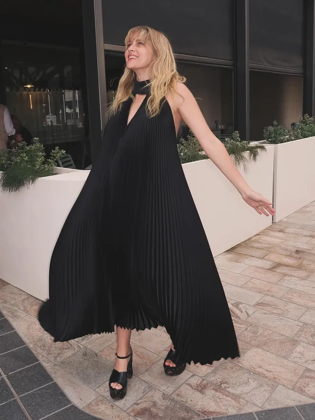 Teresa Palmer posing outdoors in a flowing black dress.
