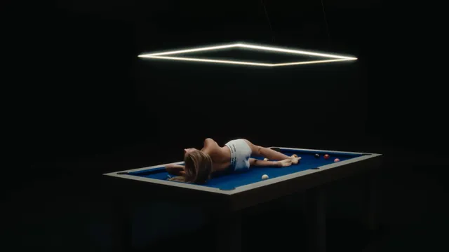 Sydney Sweeney lying on a blue platform beneath rectangular studio lights.