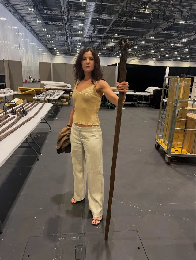 Danielle Campbell standing backstage in a pale outfit.