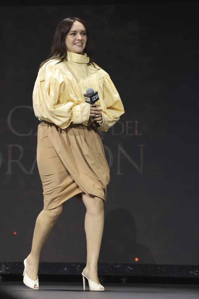 Olivia Cooke standing onstage holding a microphone.