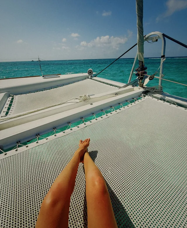 Gigi Hadid relaxing barefoot on a boat above blue water.