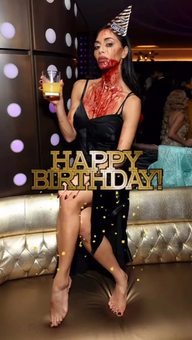 Nicole Scherzinger sitting barefoot in a dark dress at a birthday celebration.