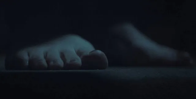 Elisha Cuthbert showing a bare foot in a dimly lit film scene.