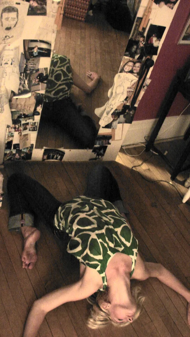 Lana Del Rey lying on a wooden floor with her bare soles raised.