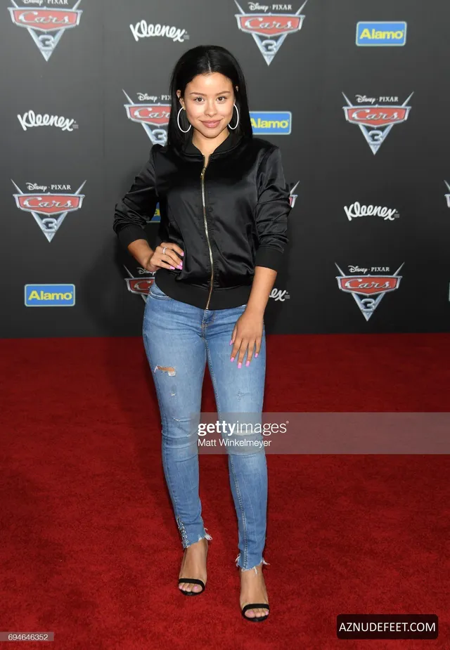 Cierra Ramirez in a black jacket, jeans and heeled sandals at a film premiere.