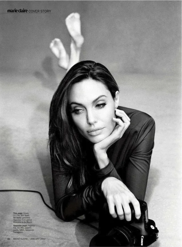 Angelina Jolie a monochrome portrait holding a camera with her feet raised.