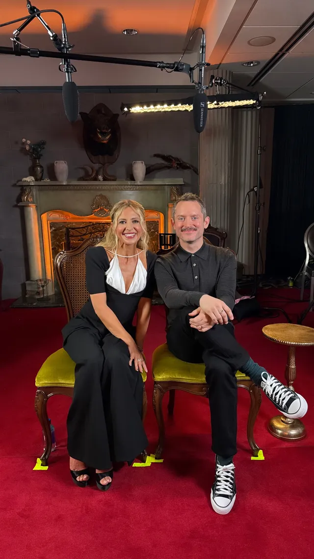 Sarah Michelle Gellar sitting beside another person in a black outfit and open-toe heels.