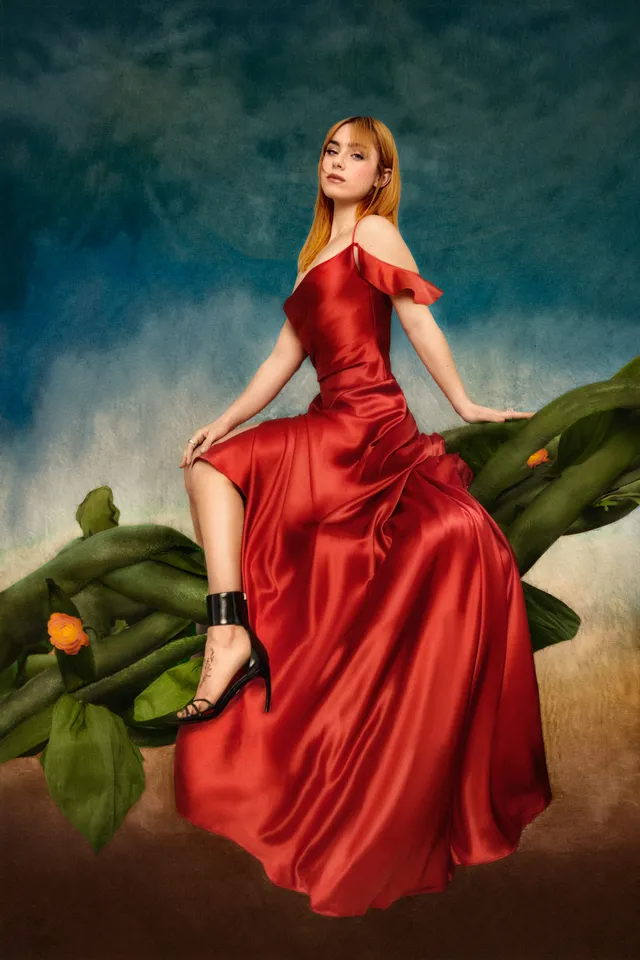 Clara Galle posing in a long red gown and black heels for a portrait.