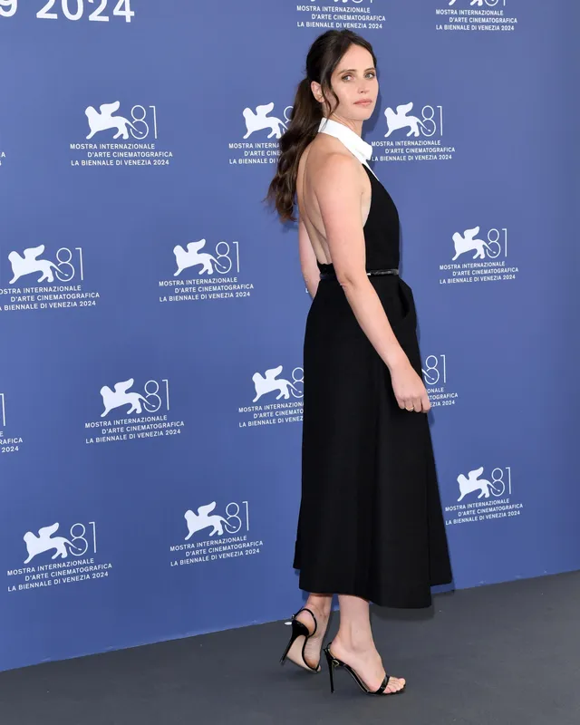 Felicity Jones turning at a film festival in a black dress.