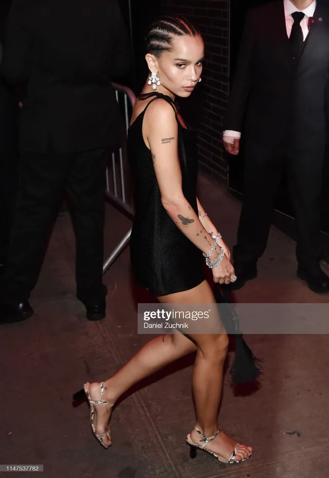 Zoë Kravitz turning toward cameras in a black dress.
