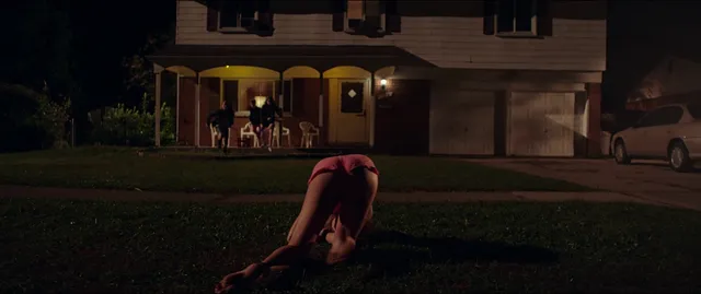 Maika Monroe kneeling barefoot on a lawn in a scene.