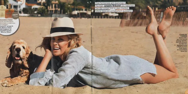 Charlize Theron lying outdoors beside a dog with her feet raised.
