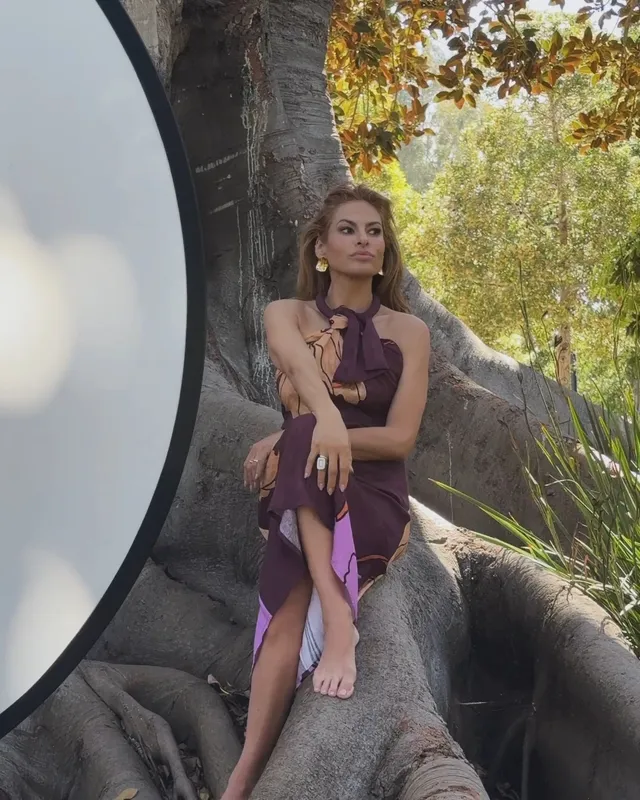 Eva Mendes sitting on rocks beside a studio reflector.