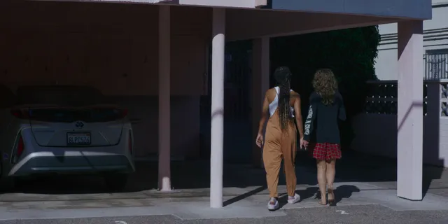 Odessa A'zion walking beside a companion in black heels in a scene.