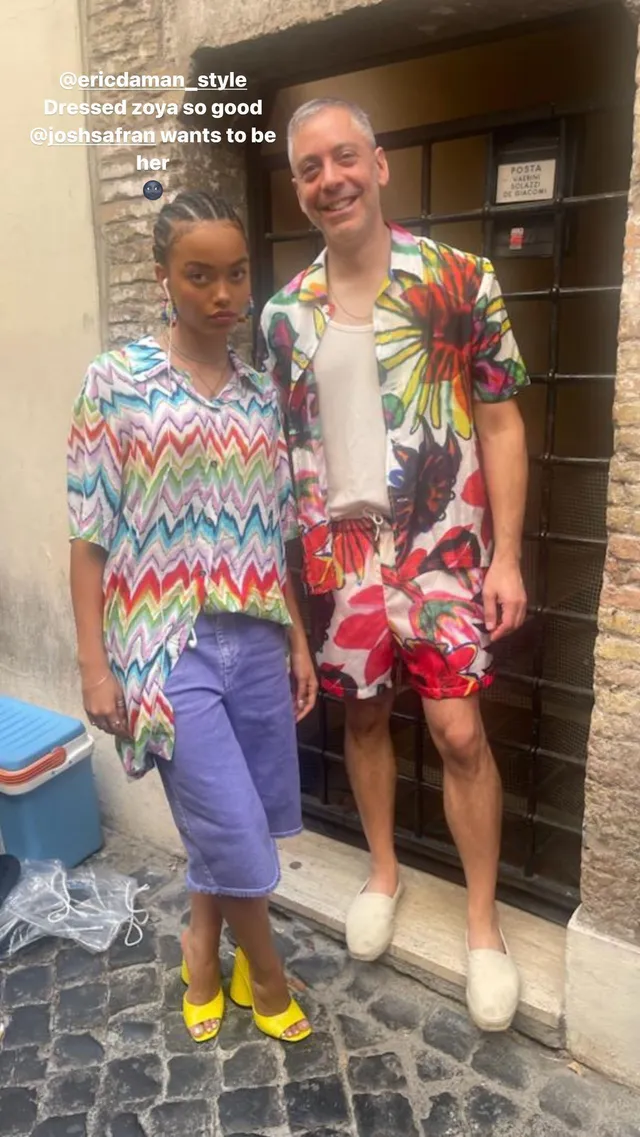Whitney Peak posing beside a man in a patterned shirt, purple shorts and yellow heels.