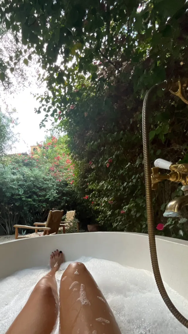 Tessa Thompson relaxing in a garden bathtub.