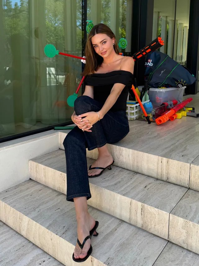 Miranda Kerr a black outfit and sandals on outdoor steps.