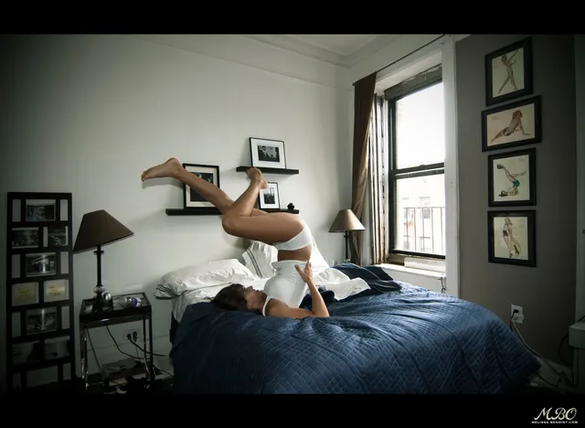 Melissa Benoist reclining barefoot on a bed with soles raised.
