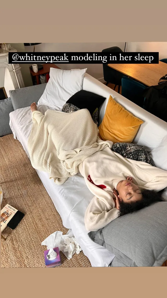 Whitney Peak reclining barefoot on an indoor sofa.