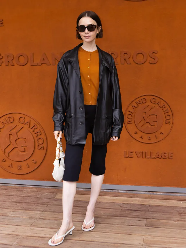 Lily Collins posing in a jacket and cropped trousers with pale heels.