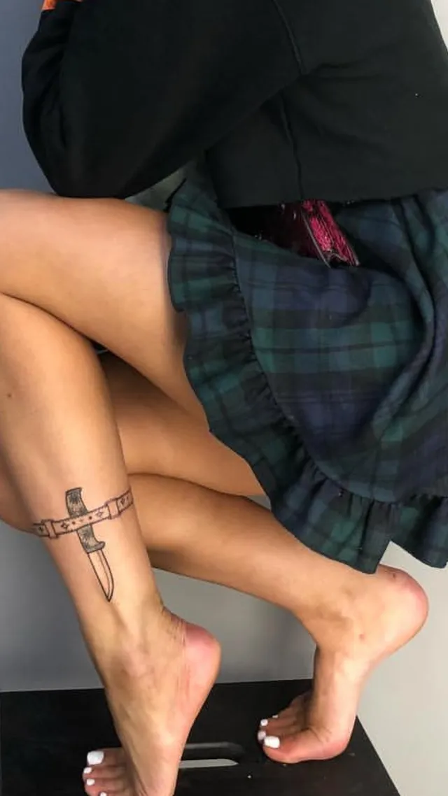Halsey a close-up of tattooed bare feet beneath a plaid skirt.