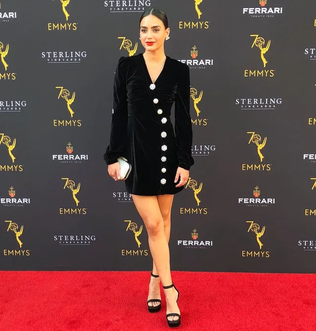Melissa Barrera posing in a black dress and platform heels.