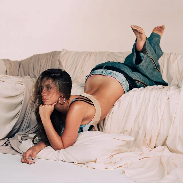 Tate McRae lying on a sofa with bare feet raised.