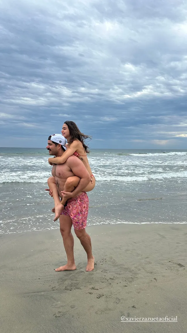 Melissa Barrera being carried barefoot on a man's back at the beach.