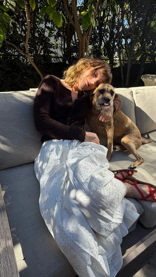 Leighton Meester sitting on a patio sofa beside a dog.