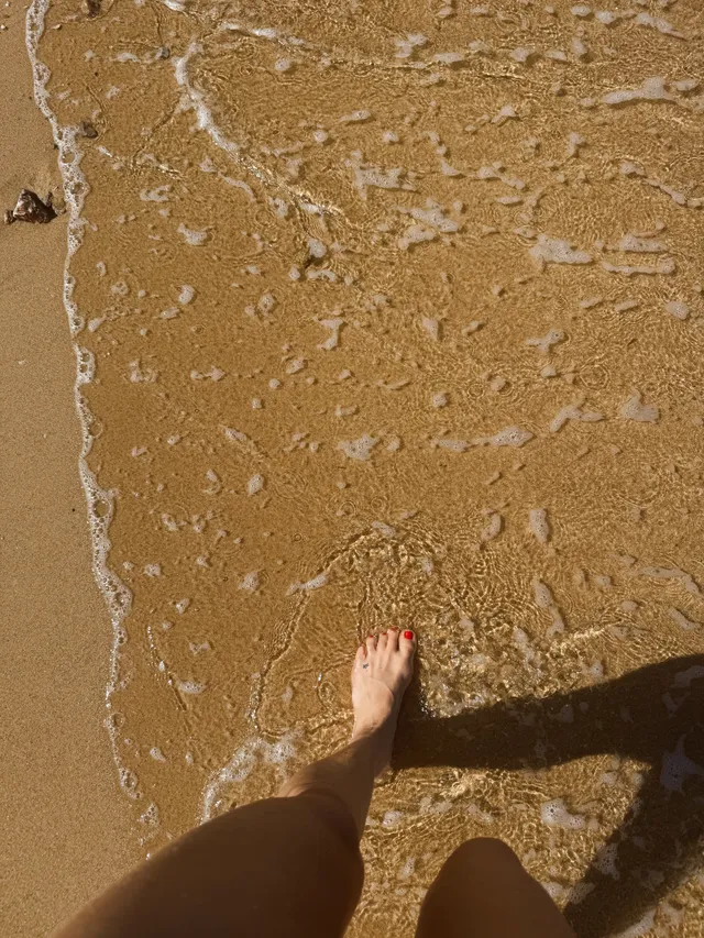 Kate Hudson standing at the edge of shallow water.