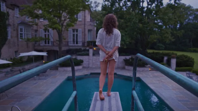 Odessa A'zion standing barefoot on a diving board in a scene.