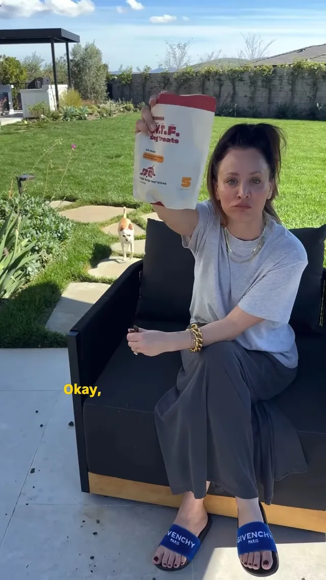 Kaley Cuoco sitting outside with food while wearing blue slides.