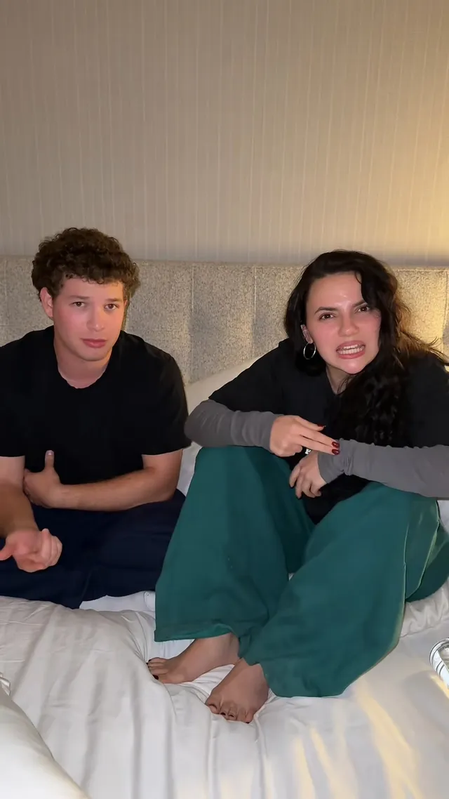 Dafne Keen sitting barefoot on a bed beside a friend.
