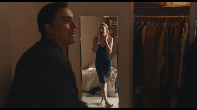 Sarah Pidgeon standing barefoot in a black dress beside a man.