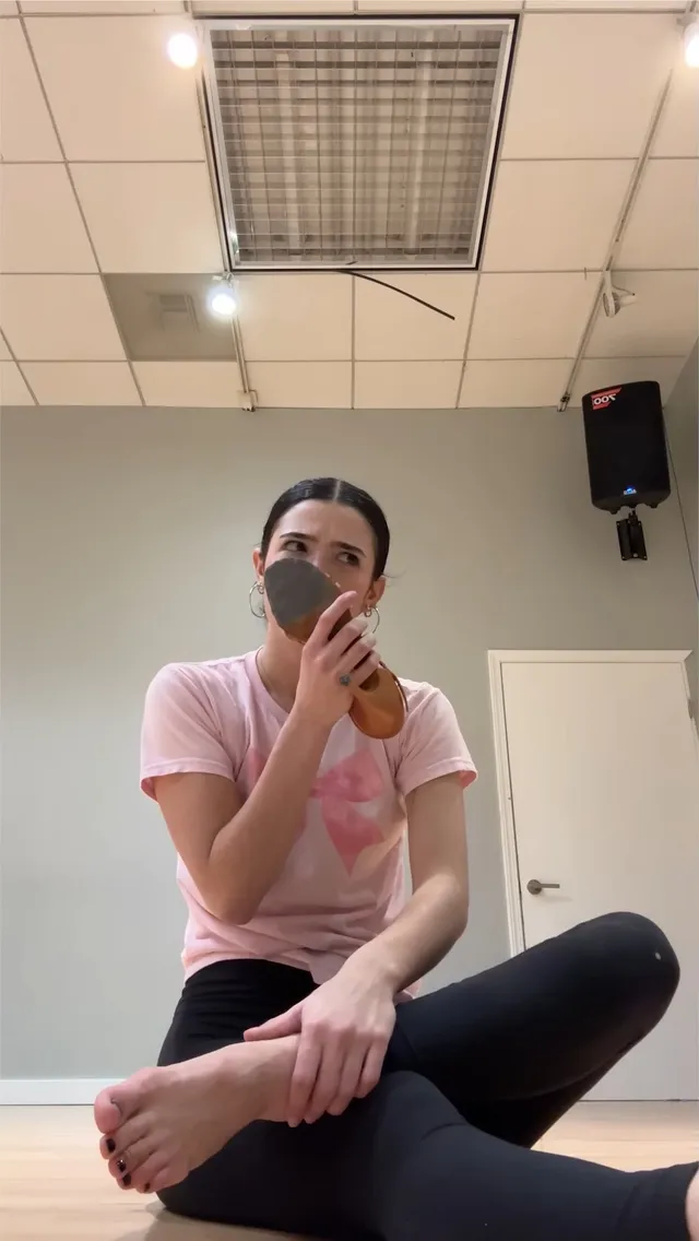 Charli D’Amelio sitting barefoot on a rehearsal-room floor.