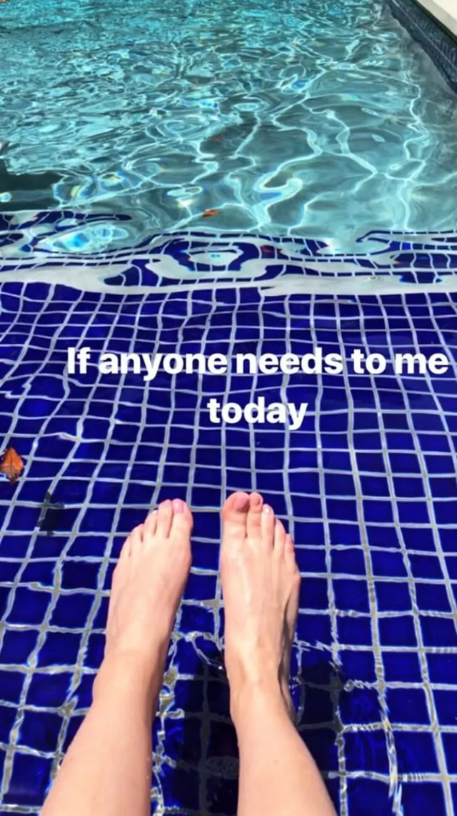 Sarah Michelle Gellar resting her bare feet beside a tiled swimming pool.