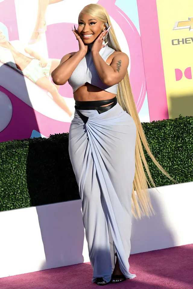 Nicki Minaj posing at an event in a long skirt and black platform heels.
