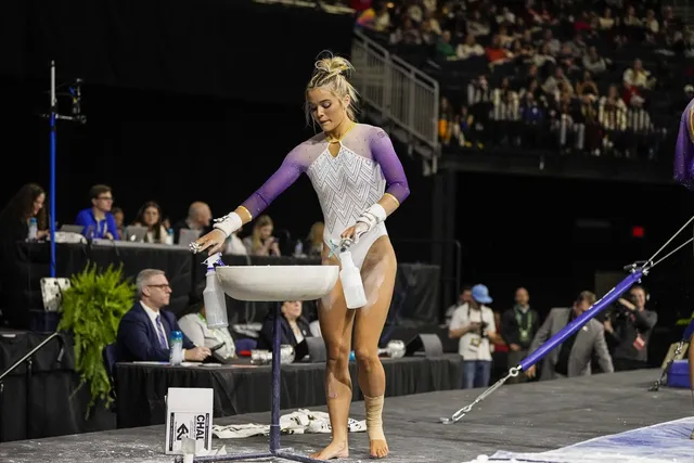 Olivia Dunne standing beside gymnastics equipment at a competition.