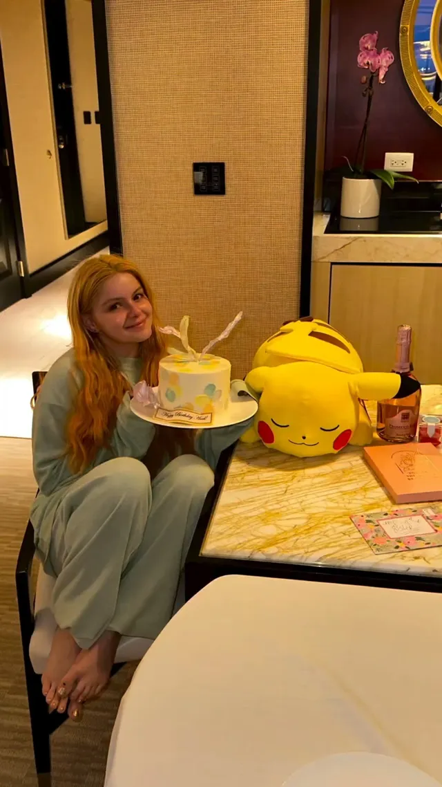 Ariel Winter sitting beside a birthday cake in a dressing room.