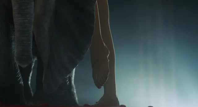 Eva Green dangling a bare foot while seated in a film scene.