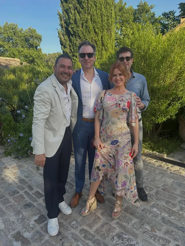 Isla Fisher posing with companions outdoors in a patterned outfit.
