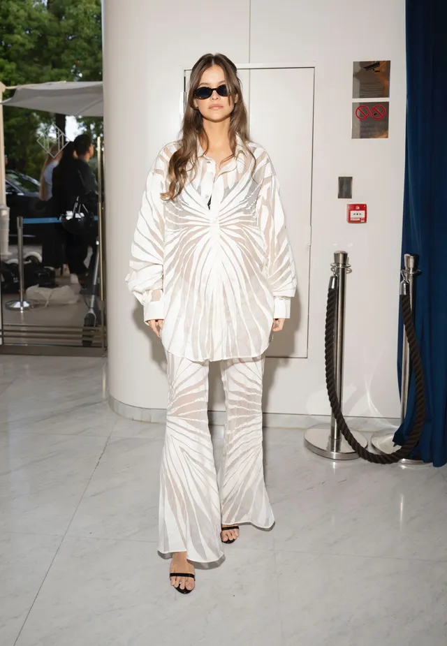 Barbara Palvin wearing a pale suit and black strappy heels.